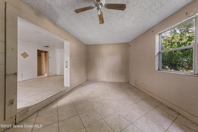 3774 Brockington Cir, Cocoa, FL 32926 - spare room featuring a textured ceiling, ceiling fan, light tile patterned floors, and wooden walls