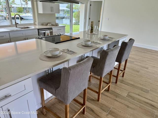 57 Riverview Ln, Cocoa Beach, FL 32931 - kitchen featuring a sink, a kitchen breakfast bar, light wood-type flooring, and white cabinets