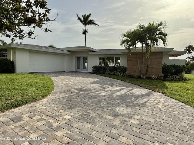57 Riverview Ln, Cocoa Beach, FL 32931 - view of front of house featuring french doors, decorative driveway, and stucco siding