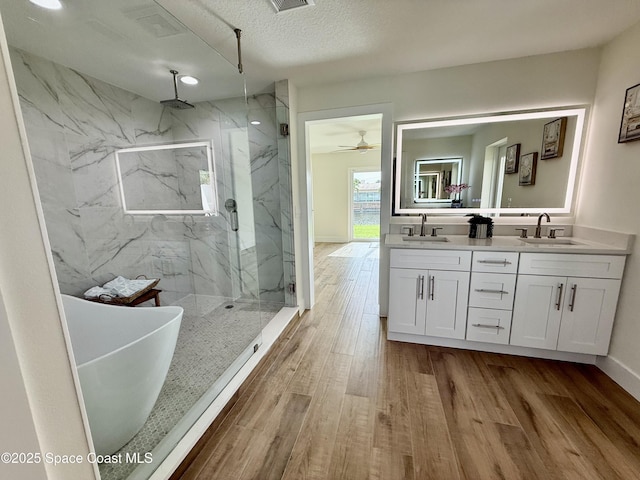 57 Riverview Ln, Cocoa Beach, FL 32931 - full bathroom featuring a marble finish shower, double vanity, wood finished floors, a freestanding bath, and a textured ceiling