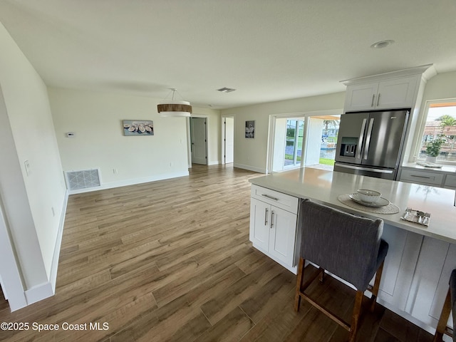 57 Riverview Ln, Cocoa Beach, FL 32931 - kitchen with stainless steel refrigerator with ice dispenser, white cabinets, light wood-style floors, and open floor plan
