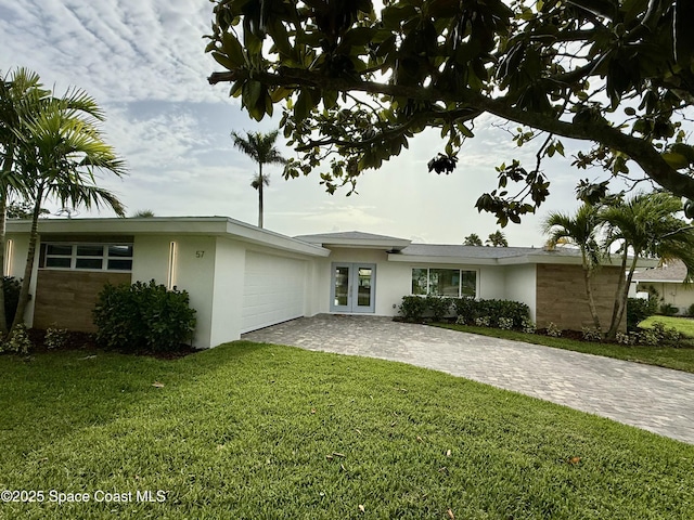 57 Riverview Ln, Cocoa Beach, FL 32931 - view of front facade with stucco siding, decorative driveway, french doors, a front yard, and a garage
