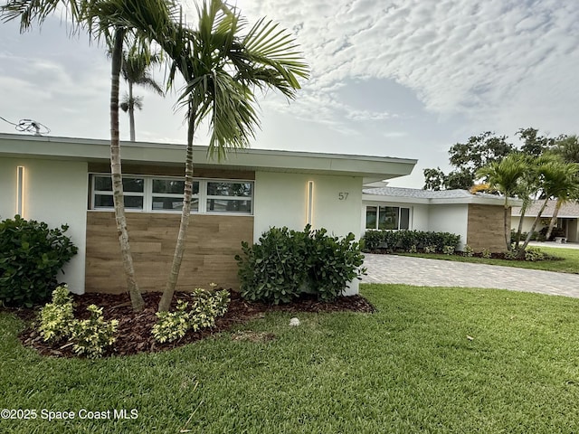 57 Riverview Ln, Cocoa Beach, FL 32931 - view of side of home featuring stucco siding, a yard, and decorative driveway