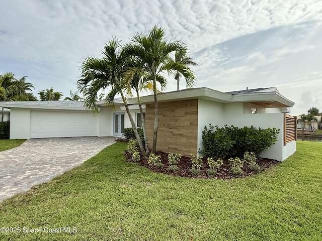 57 Riverview Ln, Cocoa Beach, FL 32931 - view of front of house featuring stucco siding, a garage, decorative driveway, and a front yard