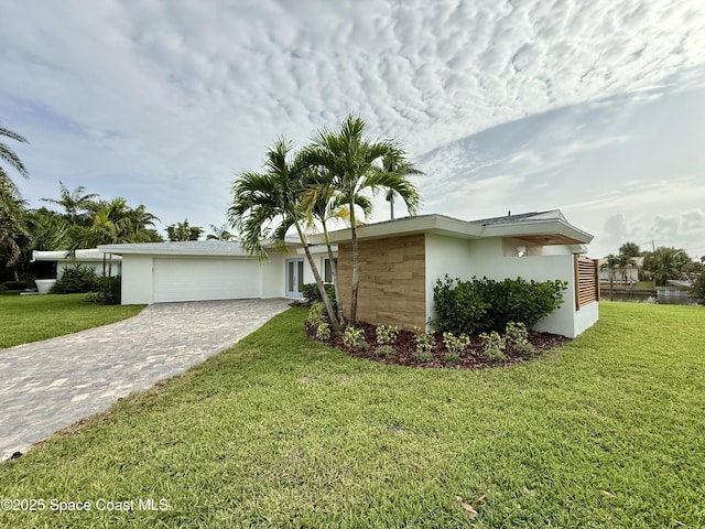 57 Riverview Ln, Cocoa Beach, FL 32931 - view of front of home with an attached garage, decorative driveway, a front yard, and stucco siding