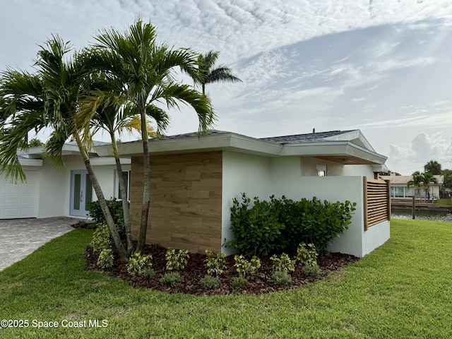 57 Riverview Ln, Cocoa Beach, FL 32931 - view of property exterior featuring french doors, stucco siding, a yard, and a garage
