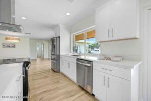 57 Riverview Ln, Cocoa Beach, FL 32931 - kitchen with stainless steel appliances, white cabinets, light countertops, light wood finished floors, and recessed lighting