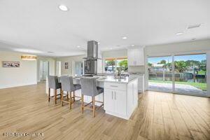 57 Riverview Ln, Cocoa Beach, FL 32931 - kitchen with wall chimney exhaust hood, white cabinets, healthy amount of natural light, and recessed lighting