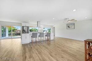 57 Riverview Ln, Cocoa Beach, FL 32931 - kitchen featuring stainless steel fridge, wood finished floors, white cabinetry, open floor plan, and a center island