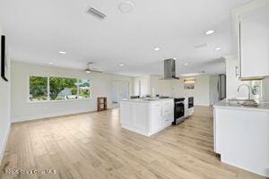 57 Riverview Ln, Cocoa Beach, FL 32931 - kitchen featuring range hood, white cabinetry, light wood-style flooring, recessed lighting, and light countertops