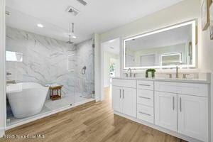 57 Riverview Ln, Cocoa Beach, FL 32931 - full bath featuring a marble finish shower, double vanity, wood finished floors, and a soaking tub