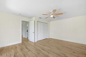 57 Riverview Ln, Cocoa Beach, FL 32931 - unfurnished bedroom featuring wood finished floors, a closet, and a ceiling fan