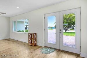 57 Riverview Ln, Cocoa Beach, FL 32931 - doorway featuring french doors, healthy amount of natural light, and wood finished floors
