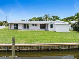 57 Riverview Ln, Cocoa Beach, FL 32931 - back of property featuring a lawn and a water view