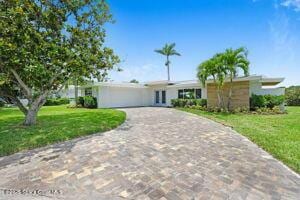 57 Riverview Ln, Cocoa Beach, FL 32931 - single story home with decorative driveway, a front yard, and a garage