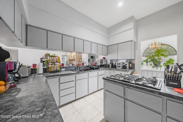 2180 Figtree Dr Unit 0, Titusville, FL 32780 - kitchen featuring black gas cooktop, a towering ceiling, dark countertops, a chandelier, and decorative backsplash