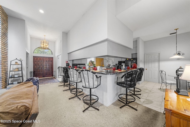2180 Figtree Dr Unit 0, Titusville, FL 32780 - kitchen featuring high vaulted ceiling, a breakfast bar, light colored carpet, a chandelier, and dark countertops