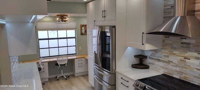 290 Paradise Blvd # 84, Indialantic, FL 32903 - kitchen featuring stainless steel appliances, wall chimney range hood, white cabinets, backsplash, and light countertops