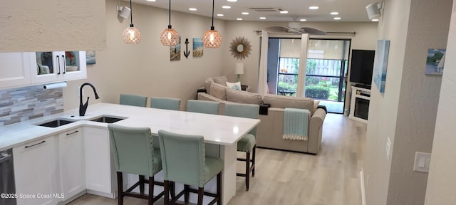 290 Paradise Blvd # 84, Indialantic, FL 32903 - kitchen with a sink, decorative backsplash, white cabinetry, light wood-style flooring, and light countertops