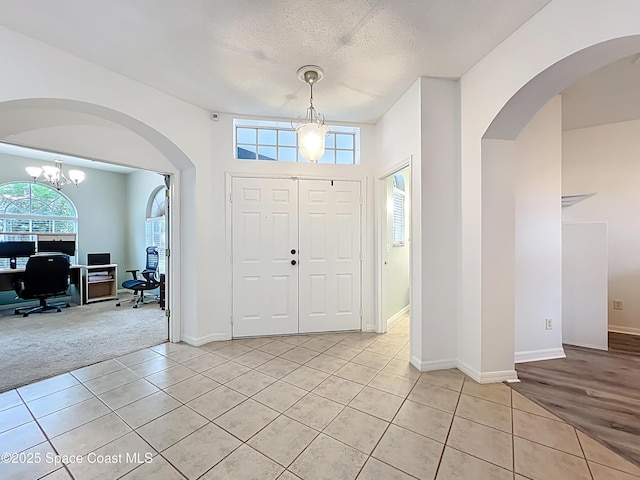 9525 Southern Garden Cir, Altamonte Springs, FL 32714 - foyer entrance featuring light tile patterned floors, arched walkways, a textured ceiling, a chandelier, and baseboards