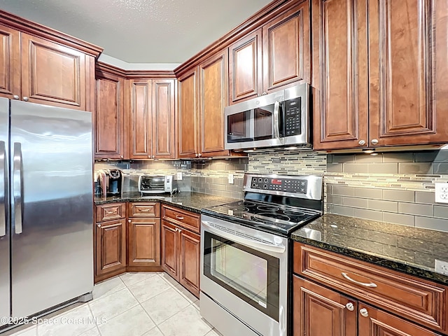 9525 Southern Garden Cir, Altamonte Springs, FL 32714 - kitchen featuring appliances with stainless steel finishes, light tile patterned floors, tasteful backsplash, dark stone countertops, and brown cabinetry