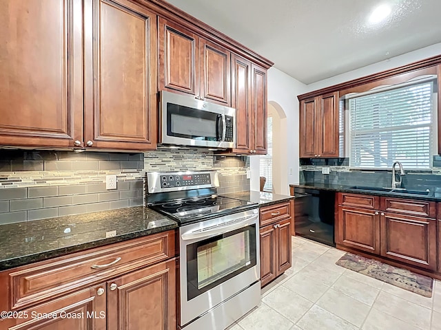 9525 Southern Garden Cir, Altamonte Springs, FL 32714 - kitchen featuring stainless steel appliances, a sink, backsplash, arched walkways, and dark stone counters