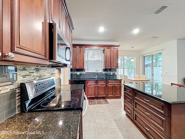 9525 Southern Garden Cir, Altamonte Springs, FL 32714 - kitchen featuring stainless steel appliances, a sink, decorative backsplash, a textured ceiling, and dark stone counters