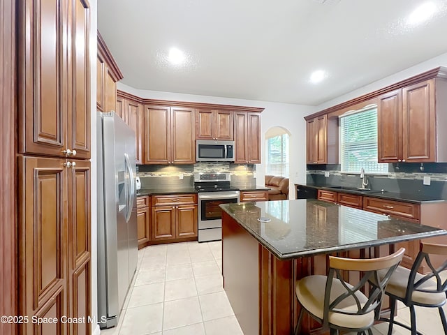 9525 Southern Garden Cir, Altamonte Springs, FL 32714 - kitchen featuring appliances with stainless steel finishes, a sink, backsplash, arched walkways, and a breakfast bar area