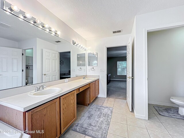 9525 Southern Garden Cir, Altamonte Springs, FL 32714 - bathroom with toilet, double vanity, tile patterned flooring, a textured ceiling, and baseboards