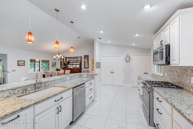 1510 Pioneer Dr, Melbourne, FL 32940 - kitchen with appliances with stainless steel finishes, vaulted ceiling, white cabinets, light marble finish floors, and a chandelier