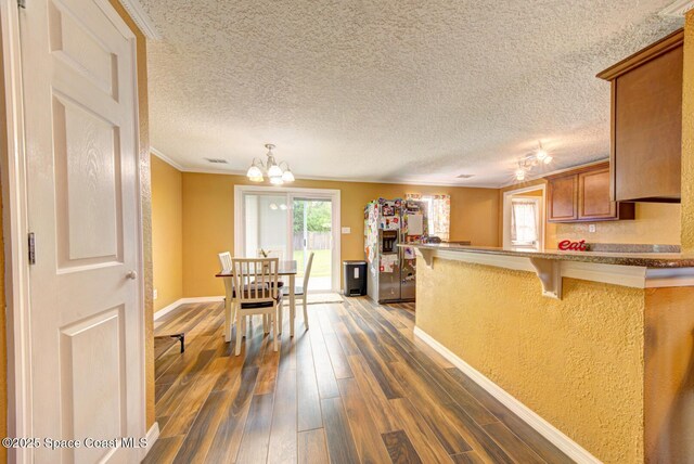 6485 Beard Ave, Cocoa, FL 32927 - kitchen featuring stainless steel fridge, baseboards, dark wood-type flooring, a peninsula, and brown cabinetry