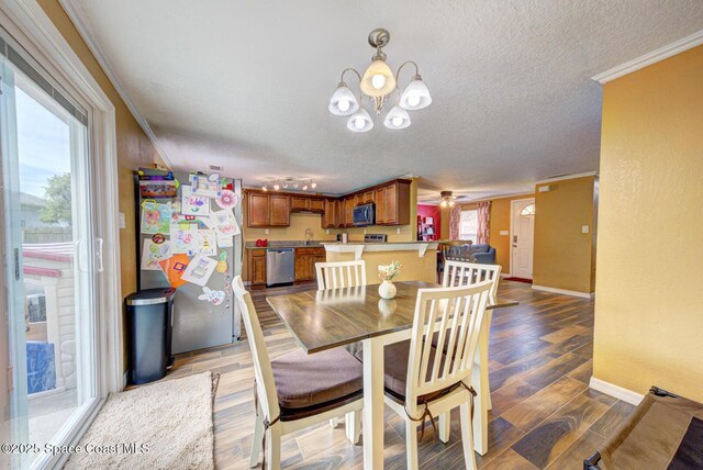 6485 Beard Ave, Cocoa, FL 32927 - dining area featuring ornamental molding, baseboards, a chandelier, a textured ceiling, and wood finished floors