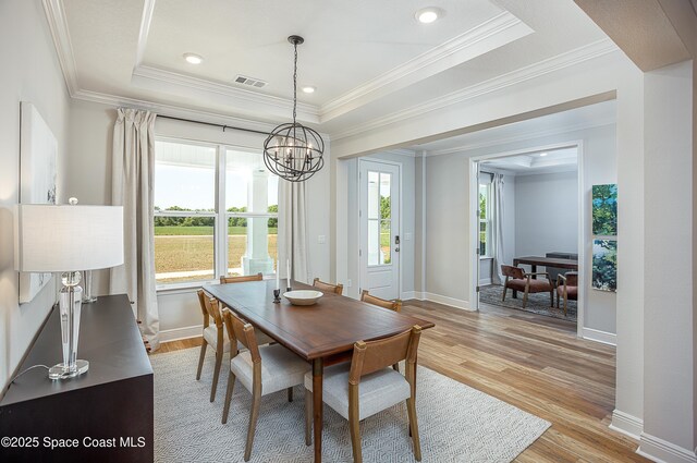 6305 Moonrise Dr, Merritt Island, FL 32953 - dining area featuring ornamental molding, a chandelier, a tray ceiling, light wood-style floors, and decorative columns