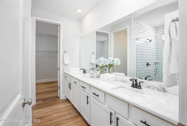 6305 Moonrise Dr, Merritt Island, FL 32953 - bathroom featuring double vanity, wood finished floors, tiled shower, a walk in closet, and recessed lighting