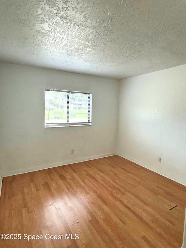 1704 University Ln Unit 703, Cocoa, FL 32922 - empty room featuring light wood finished floors, a textured ceiling, and baseboards