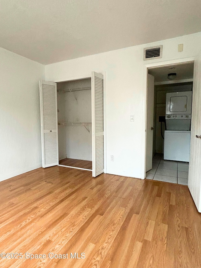 1704 University Ln Unit 703, Cocoa, FL 32922 - unfurnished bedroom featuring stacked washer and clothes dryer, light wood-type flooring, and a closet