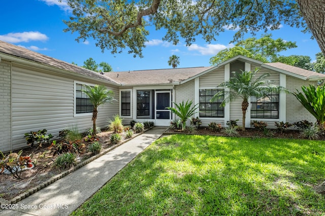 816 Pine Shadows Ave W, Rockledge, FL 32955 - view of front of house featuring brick siding, a front lawn, and roof with shingles