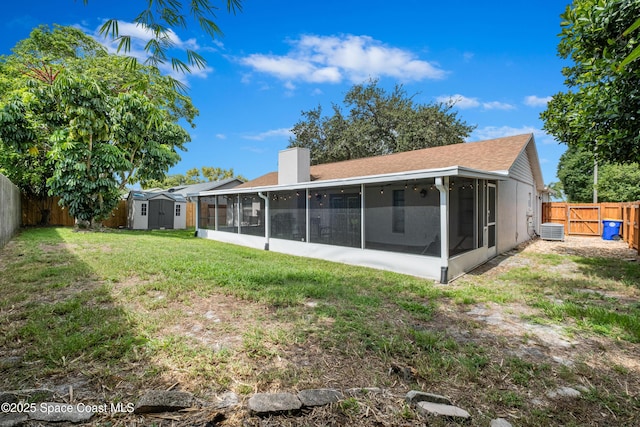 816 Pine Shadows Ave W, Rockledge, FL 32955 - back of property with a sunroom, a storage shed, a fenced backyard, a chimney, and a shingled roof