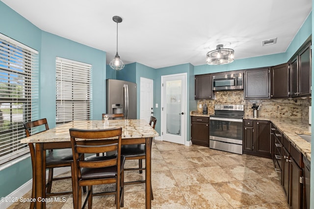 816 Pine Shadows Ave W, Rockledge, FL 32955 - kitchen with stainless steel appliances, dark brown cabinetry, backsplash, light stone countertops, and hanging light fixtures