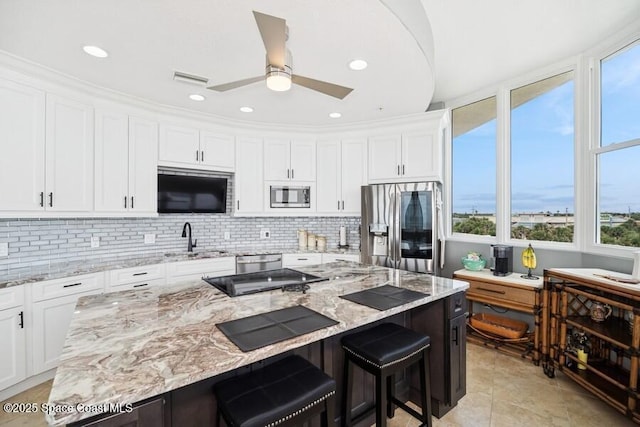 601 N Miramar Ave Unit 314, Indialantic, FL 32903 - kitchen featuring appliances with stainless steel finishes, a sink, white cabinetry, a kitchen bar, and backsplash