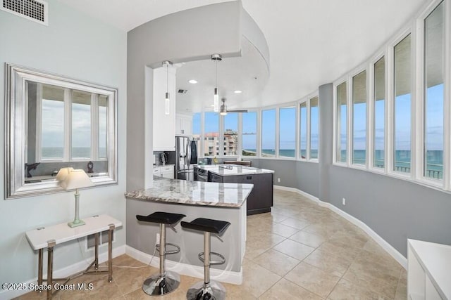 601 N Miramar Ave Unit 314, Indialantic, FL 32903 - kitchen with a center island, white cabinetry, a water view, light tile patterned floors, and stainless steel fridge