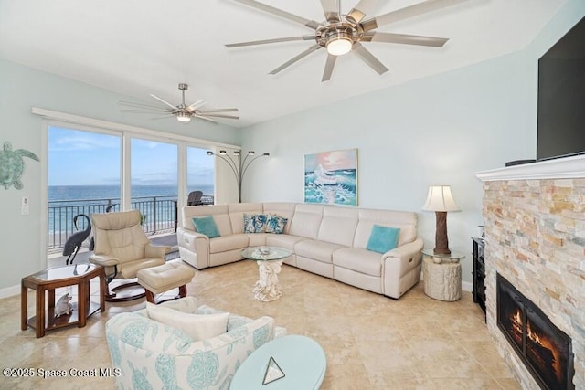 601 N Miramar Ave Unit 314, Indialantic, FL 32903 - living room with ceiling fan, a water view, a stone fireplace, baseboards, and light tile patterned floors