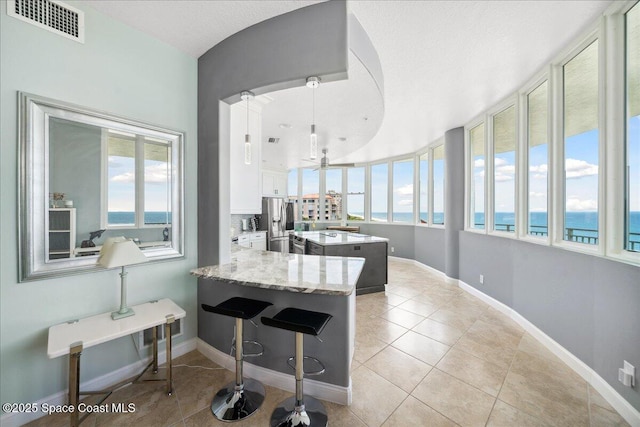 601 N Miramar Ave Unit 314, Indialantic, FL 32903 - kitchen with stainless steel refrigerator with ice dispenser, light tile patterned flooring, healthy amount of natural light, and white cabinets