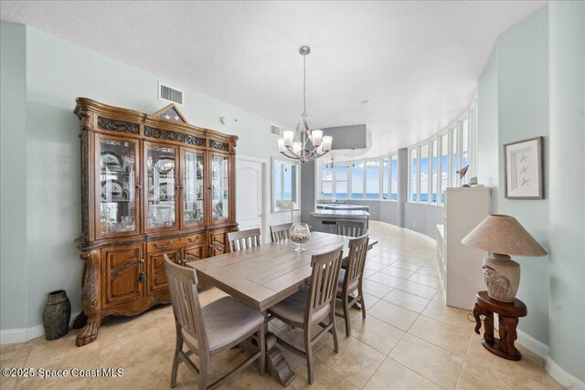 601 N Miramar Ave Unit 314, Indialantic, FL 32903 - dining area featuring a chandelier, light tile patterned flooring, baseboards, and a textured ceiling