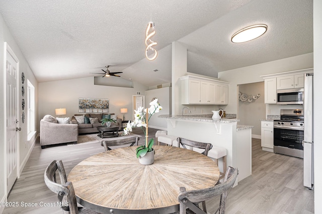 542 White Plains Ave SW, Palm Bay, FL 32908 - dining room featuring vaulted ceiling, ceiling fan, a textured ceiling, light wood-type flooring, and baseboards