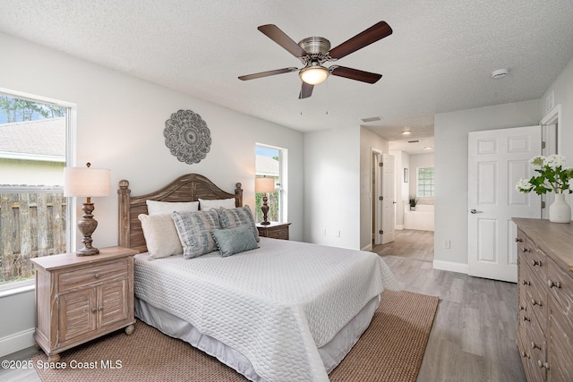 542 White Plains Ave SW, Palm Bay, FL 32908 - bedroom featuring light wood-type flooring, multiple windows, baseboards, and a textured ceiling