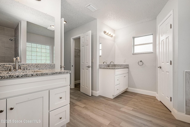 542 White Plains Ave SW, Palm Bay, FL 32908 - full bath featuring a textured ceiling, two vanities, wood finished floors, and healthy amount of natural light