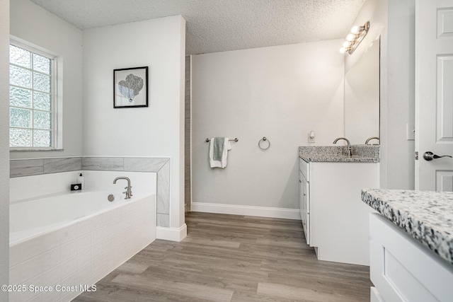 542 White Plains Ave SW, Palm Bay, FL 32908 - bathroom with vanity, a garden tub, a textured ceiling, wood finished floors, and baseboards