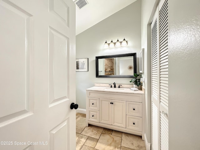 10360 Crystal Point Dr, Orlando, FL 32825 - bathroom featuring a closet, vanity, stone tile flooring, baseboards, and lofted ceiling
