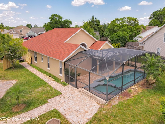 10360 Crystal Point Dr, Orlando, FL 32825 - rear view of house with a patio, stucco siding, glass enclosure, and a lawn